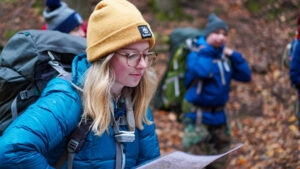 Photo of Tatum Severson reading a map with a group in the woods